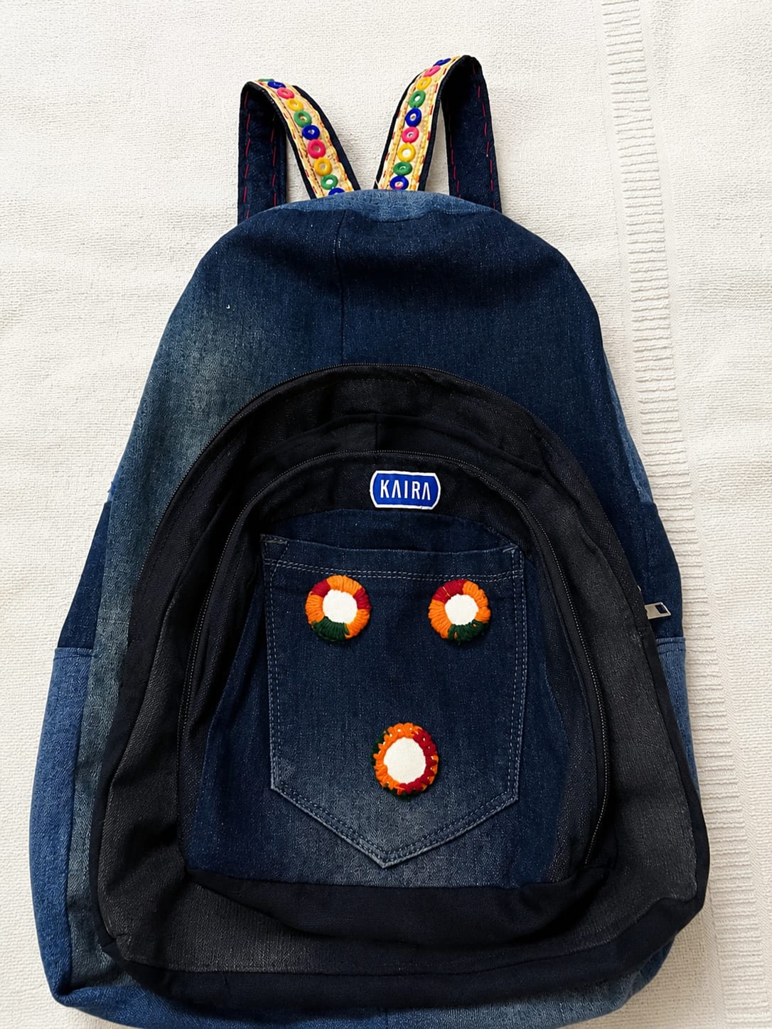Denim backpack with embroidered pocket and beaded straps
